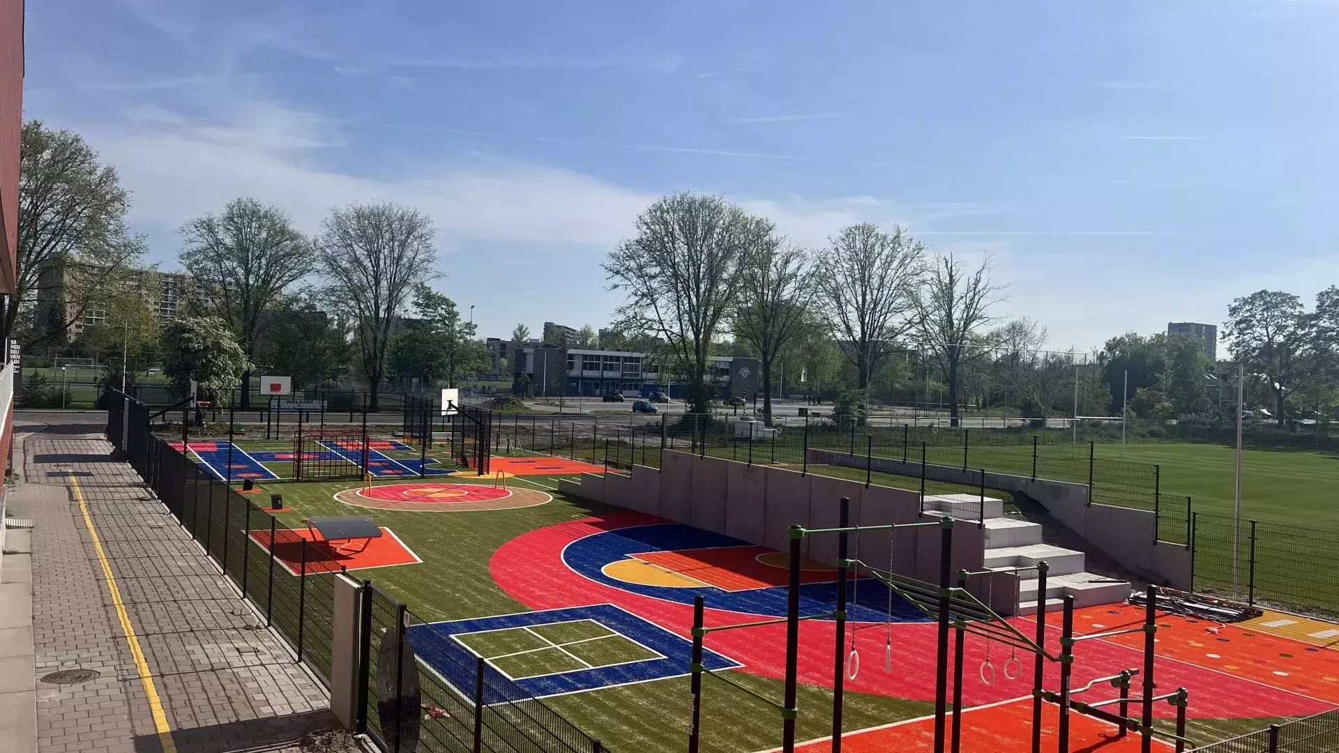 foto van skills garden in de beuk. hek met erin gekleurde kunstgrasvelden en sportattributen.